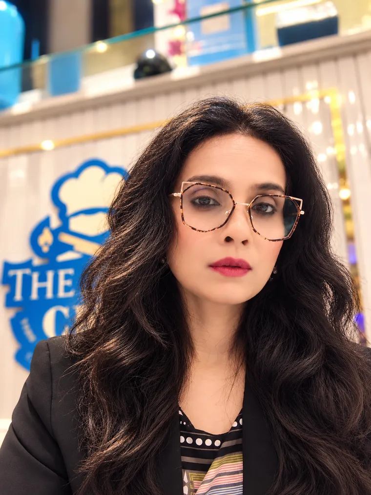 Maliha Bano at The Blue Chef, with the restaurant's logo behind her